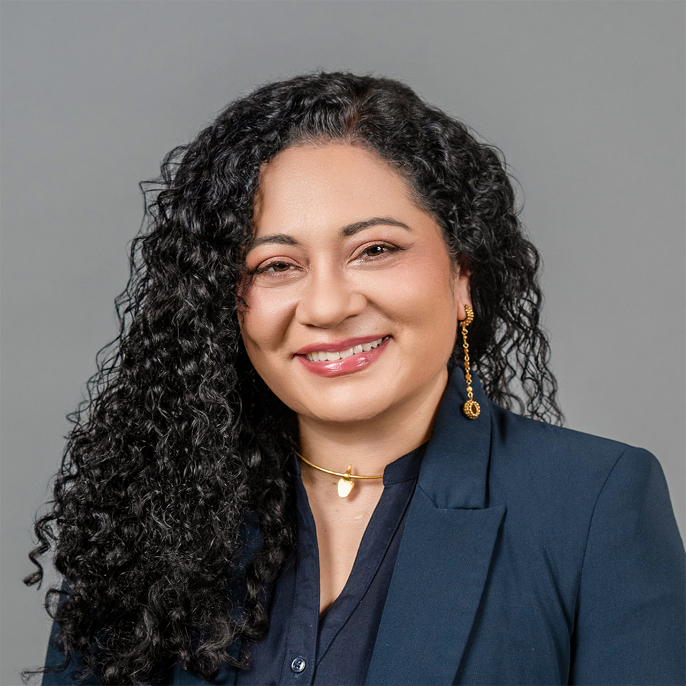 Headshot for María Elena Gavilán Alfonso, posed against a gray background wearing a dark jacket
